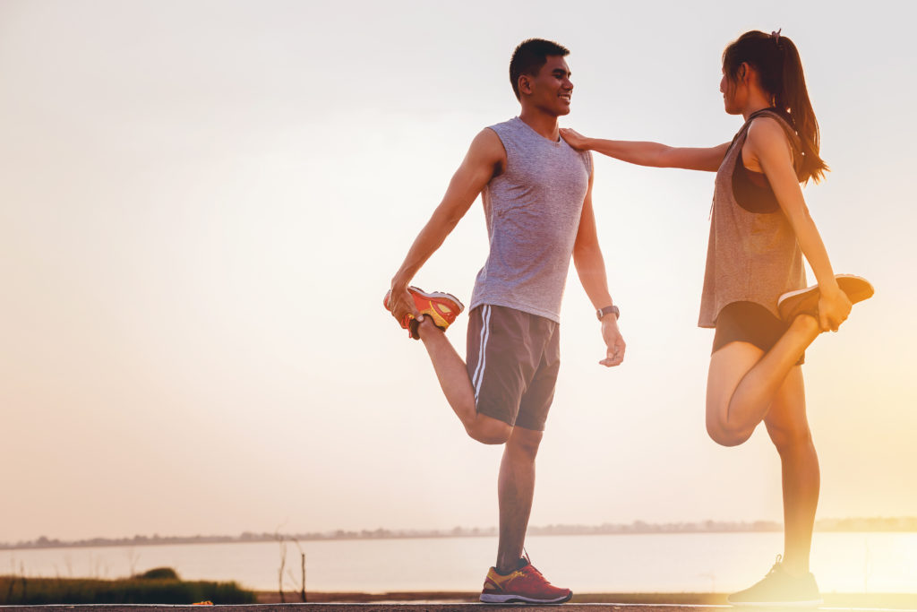 Two young couples athletes worming up for outdoor practice with sunset background